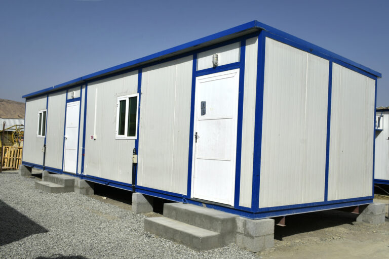 Portable cabin configured as a site office with windows and entry steps.