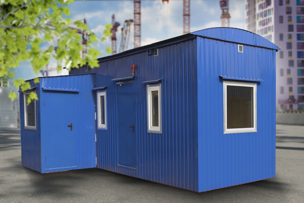 Blue portable cabin set up for employee use on a construction site.