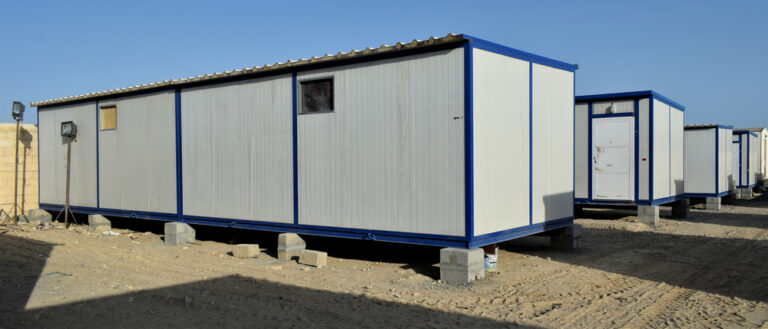 Portable modular cabin building with doors and windows installed on a gravel site.